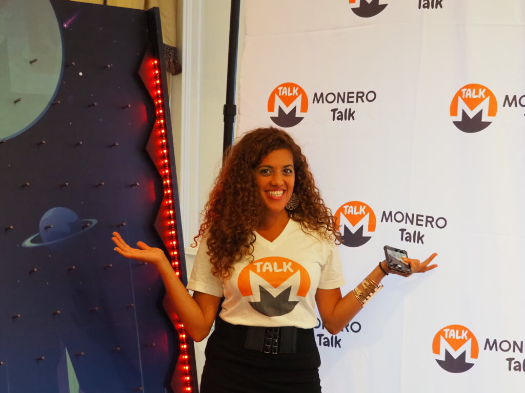 Photo d'une femme debout devant une bannière Monero Talk